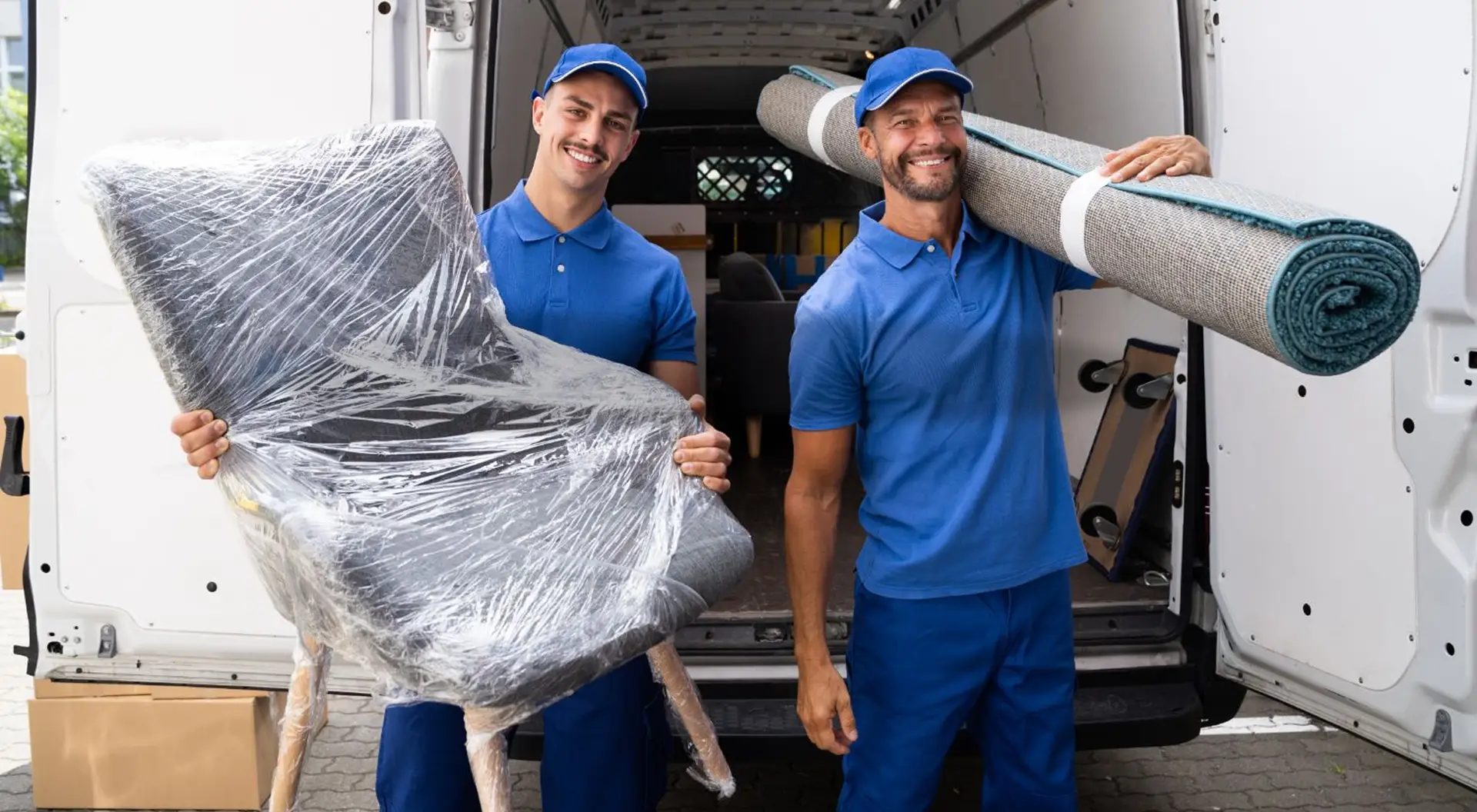 Two smiling movers standing in front of their truck